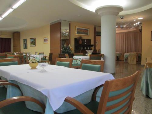 una sala da pranzo con tavolo e sedie bianchi di Hotel Due Pini a Melfi