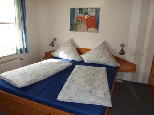 a blue bed with two pillows on top of it at Apartment-3 in Schönhagen
