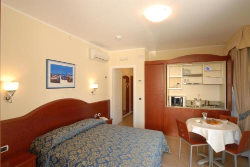 a bedroom with a bed and a table and a kitchen at Residence Costa Smeralda in Grottammare