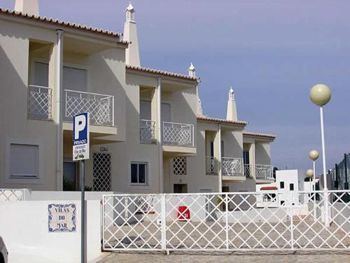 a large white house with a fence and a parking lot at Vilas do Mar in Carvoeiro