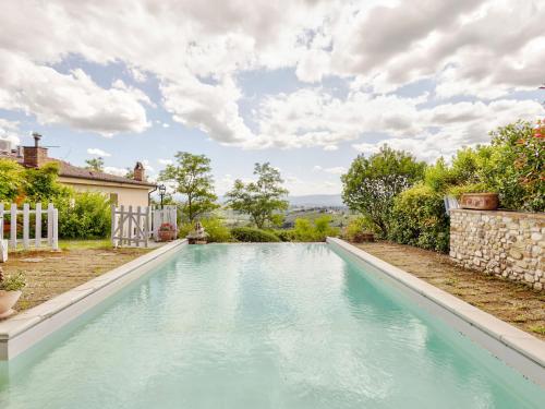 タヴァルネッレ・ヴァル・ディ・ペーザにあるCozy Holiday Home in Tavarnelle Val di Pesa with Shared Poolの青い水の家の裏庭にあるスイミングプール