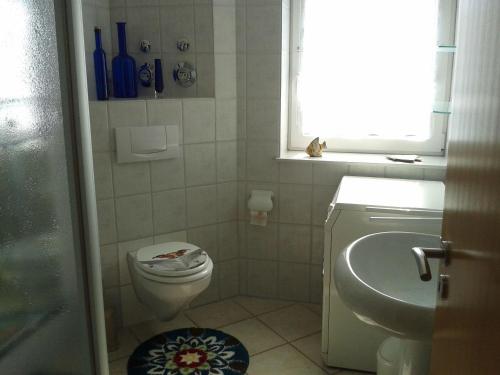 een badkamer met een toilet, een wastafel en een raam bij Wohnen-mit-Deichblick-fuer-Geniesser in Schönberger Strand