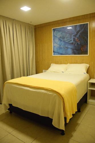 um quarto com uma cama grande e um cobertor amarelo em Ana marinho flat 702 em Natal