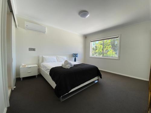 a white bedroom with a bed and a window at Townsville Wistaria Spacious Home in Townsville
