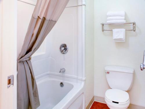 a white bathroom with a toilet and a bath tub at Travelodge by Wyndham Miles City in Miles City