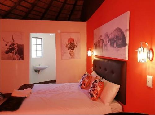 a bedroom with an orange wall with a bed and a sink at Nogixa Lodge in Umzimkulu