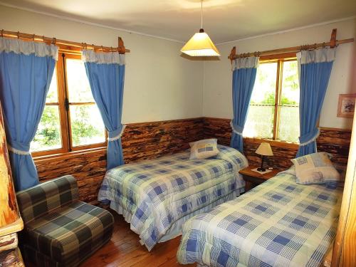 1 dormitorio con 2 camas, silla y ventanas en Lodge Mirador, en Chillán