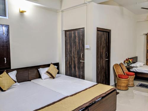 a bedroom with a bed and two doors and chairs at Townhouse - The Urban Inn in Dibrugarh