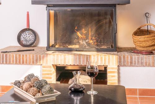a table with a glass of wine and a fireplace at Ca La Conxita in Las Escaulas