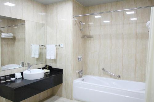 La salle de bains est pourvue d'un lavabo, d'une baignoire et de toilettes. dans l'établissement Zambia Golden Peacock Hotel, à Lusaka