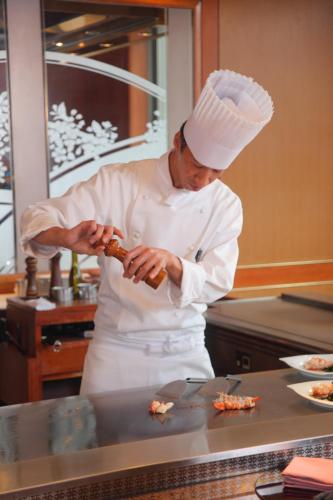 a chef standing in a kitchen preparing food at Hotel Metropolitan Nagano in Nagano