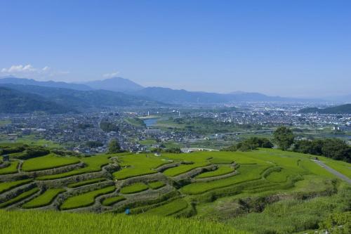 a view of a green hill with a city at Hotel Metropolitan Nagano in Nagano