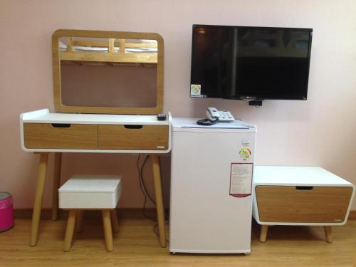 a small desk with a television and a refrigerator at Jeju R Hotel & Guesthouse in Jeju