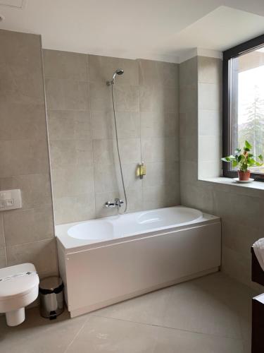 a bathroom with a white tub and a toilet at Edelweiss Apartments SILVER RESORT POIANA BRASOV in Poiana Brasov