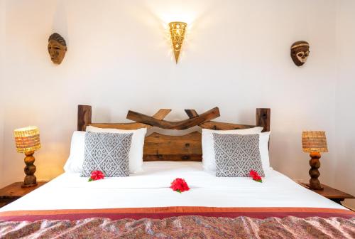 a bedroom with a bed with red flowers on it at Kibanda Natural Kendwa Villa in Kendwa