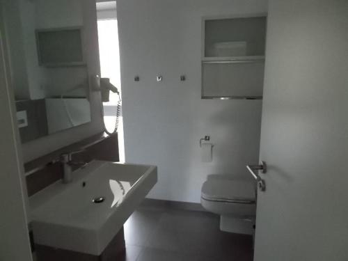 a white bathroom with a sink and a toilet at Modernes-Wohnen-im-Bungalow in Quickborn