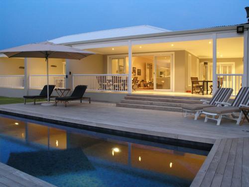 a patio with chairs and an umbrella next to a pool at Kowie River Guest House in Port Alfred