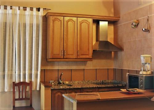 uma cozinha com armários de madeira e uma bancada em La Cabachuela em Casares de las Hurdes