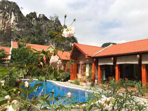 a villa with a swimming pool and mountains in the background at Tam Coc Friendly Homestay in Ninh Binh