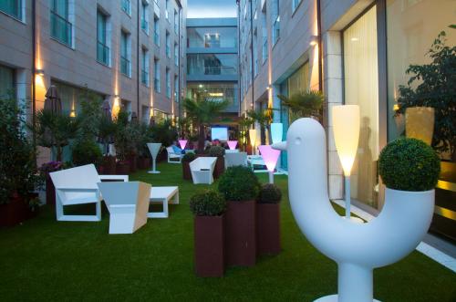 a courtyard in a building with white furniture and plants at Gran Hotel Don Manuel in Cáceres