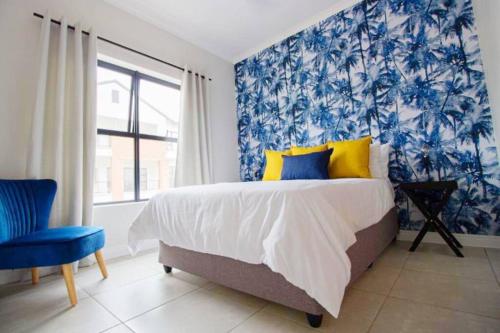 Schlafzimmer mit einem Bett mit blauen und gelben Kissen in der Unterkunft Ballito Hills Villa in Ballito