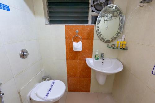 a bathroom with a sink and a toilet and a mirror at KSTDC Mayura Durg Chitradurga in Chitradurga