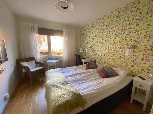 1 dormitorio con 1 cama grande y papel pintado con motivos florales en Nynäsgården Hotell & Konferens, en Nynäshamn