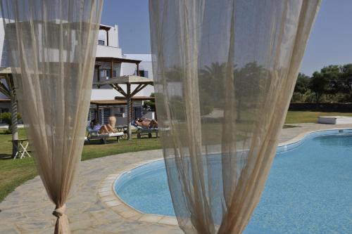 a curtain is standing next to a swimming pool at Ammos Naxos Exclusive Apartments & Studios in Naxos Chora