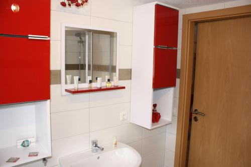 a bathroom with a sink and a mirror and red cabinets at Ferienwohnung-Schrammsteinblick in Lichtenhain