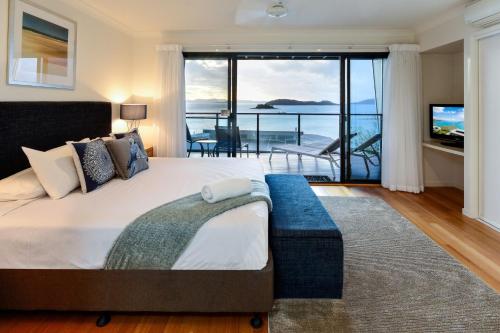 een slaapkamer met een groot bed en uitzicht op de oceaan bij Shorelines 31 Renovated Upmarket Two Bedroom Apartment With Ocean Views And Buggy in Hamilton Island