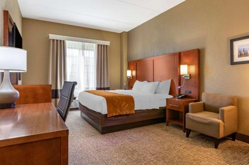 Habitación de hotel con cama, escritorio y silla en Comfort Suites Grand Rapids South, en Grand Rapids