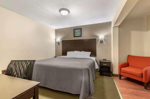Habitación de hotel con cama y silla roja en Rodeway Inn Lake George Outlets, en Lake George