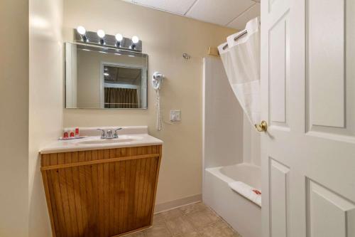 a bathroom with a sink and a mirror and a tub at Rodeway Inn Lake George Outlets in Lake George