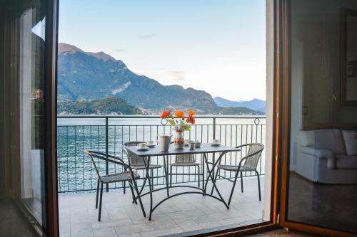 a table and chairs on a balcony with a view of the water at Bellagio Villas in Lezzeno