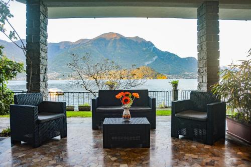 a patio with two chairs and a table with a vase of flowers at Bellagio Villas in Lezzeno
