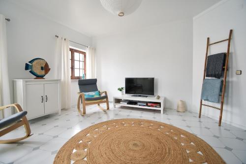 a living room with a tv and a rug at A Casa na Foz - West is the Best ! in Foz do Arelho