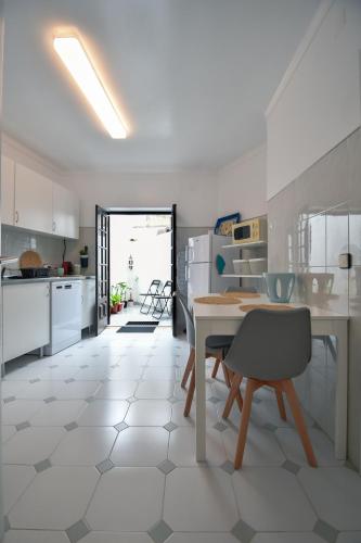 a kitchen with white cabinets and a table and chairs at A Casa na Foz - West is the Best ! in Foz do Arelho