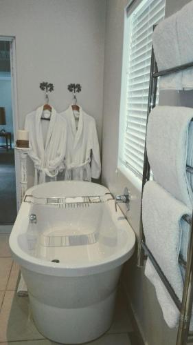 a bathroom with a white tub and towels on racks at Kowie River Guest House in Port Alfred