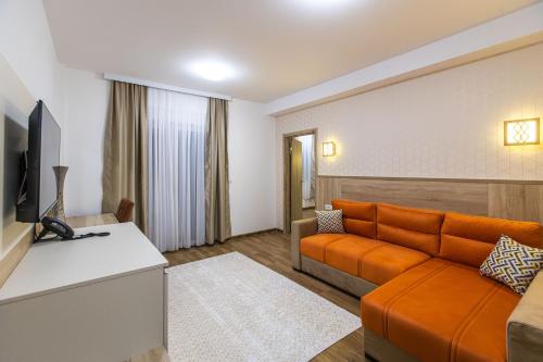 sala de estar con sofá naranja y TV en Aqua Spa Termale, en Novi Pazar