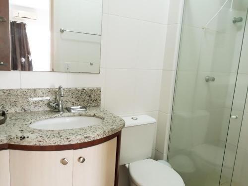 um banheiro com uma pia, um vaso sanitário e um espelho em Cobertura em Canasvieiras - Vista para o Mar - 50 mtrs da Praia - Centro Canasvieiras em Florianópolis