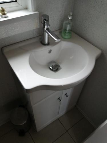 a white sink in a bathroom with a window at White Lodge in Caernarfon