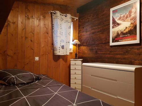 1 dormitorio con paredes de madera, 1 cama y vestidor en Petit chalet savoyard, en Domancy