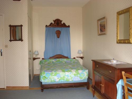 a bedroom with a bed with a blue curtain and a dresser at Gite de Cohignac in Berric