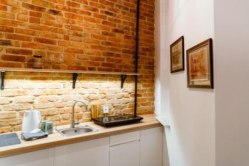 a kitchen with a brick wall and a sink at Kamienica1899 in Szczecin