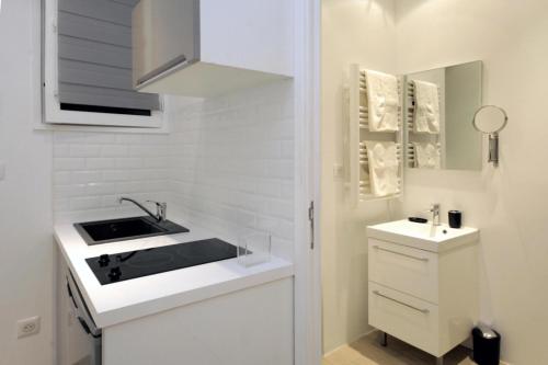 - une petite cuisine blanche avec un évier et un miroir dans l'établissement C005-Studette au centre Cannes, à Cannes
