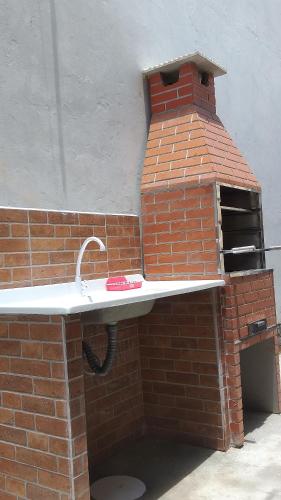 un horno de ladrillo con fregadero en una pared de ladrillo en Residencial Chalés Riviera, en Matinhos