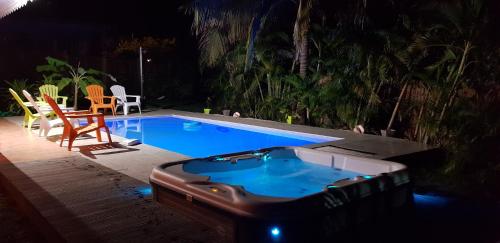 a swimming pool at night with a chair and a table at Villa Bois d'Inde in Le Diamant