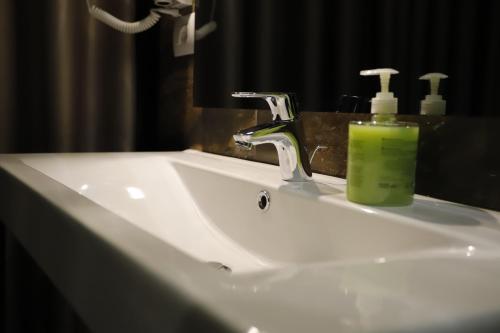 a bathroom sink with a green soap bottle on it at Admiral Hotel in Elbasan