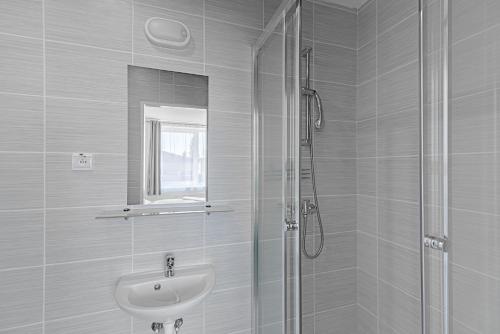 a white bathroom with a sink and a shower at Garni Hotel 31 in Spišská Nová Ves