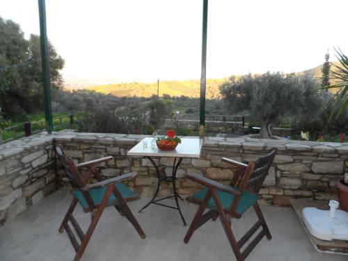 a table and chairs on a patio with a stone wall at Sivas Apartments-Studios,Sigelakis with very nice view in Sívas
